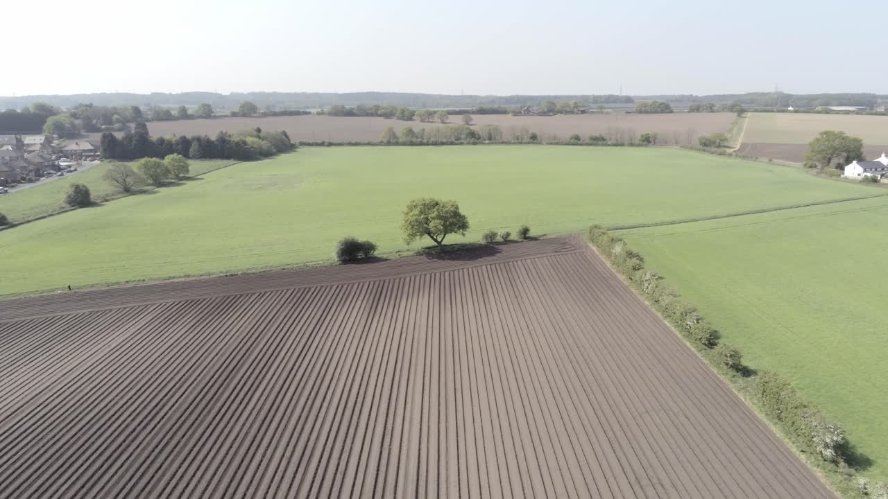 Drohnen-Luftaufnahme von Reihen fruchtbaren britischen Ackerlandes mit Furchen in der Landschaft, mit aufsteigender Rückwärtsbewegung