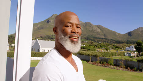 front view of mature caucasian man having coffee in balcony at home 4k