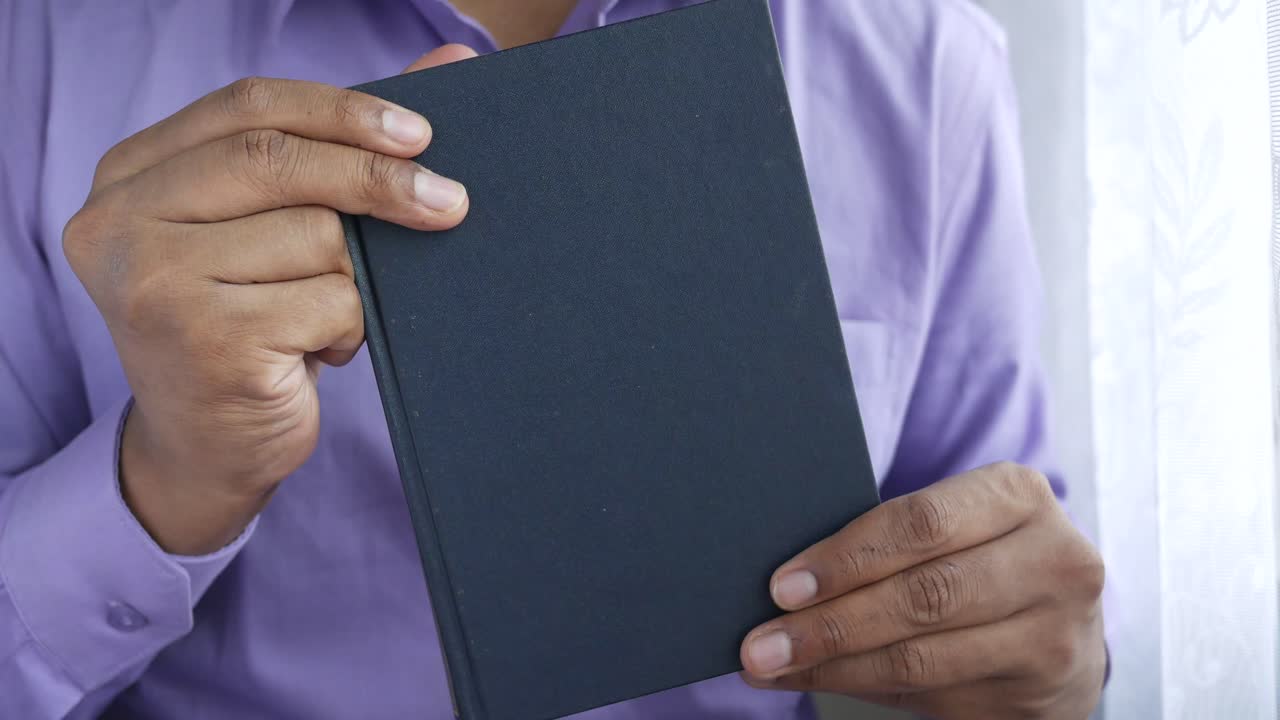 persona que sostiene un libro azul oscuro