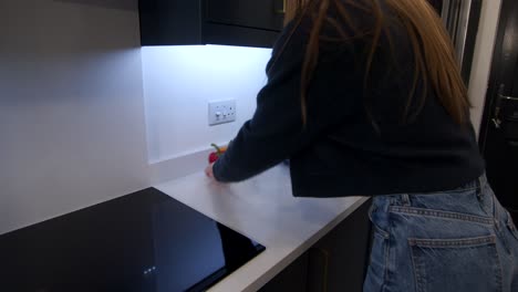 Female-model-wiping-down-a-white-quartz-worktop-by-a-induction-cooker-top-in-a-kitchen