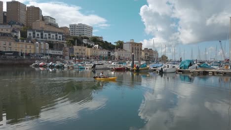 hombre navega en kayak por el puerto de torquay hacia el mar