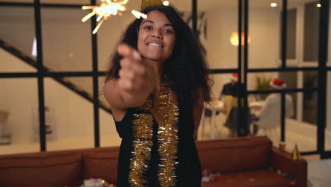 beautiful black woman holding a sparkler at new year's eve party