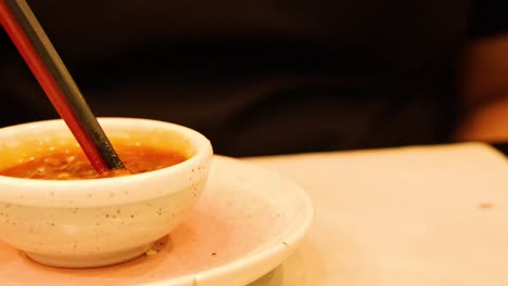 chopsticks stirring sauce in a small bowl