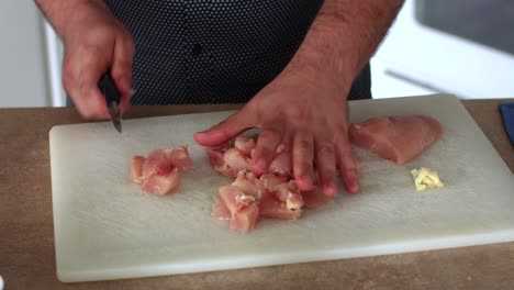 pollo en cubos en una tabla de cortar blanca