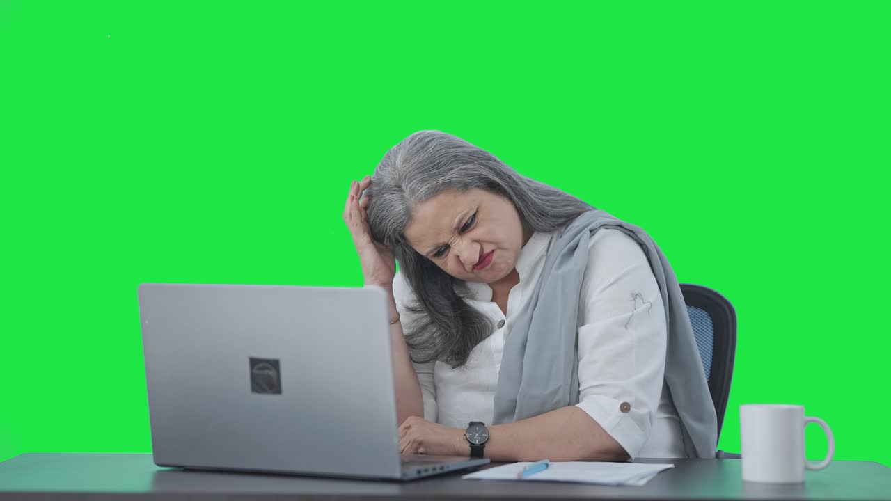 confundida gerente femenina india senior trabajando en la pantalla verde de la computadora portátil