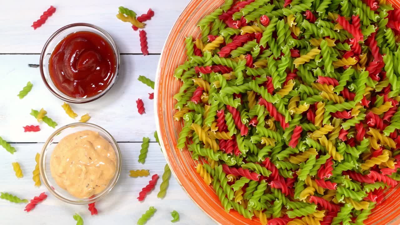 다채로운 익히지 않은 원시 이탈리아 푸실리 파스타가 접시에서 회전 테이블에서 천천히 회전합니다.