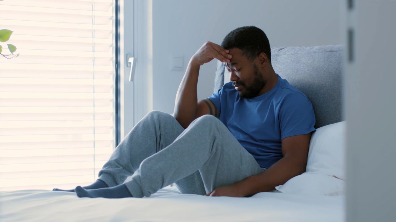 Stressed Young Man Sitting on Bed in Bedroom