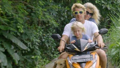 family driving scooter in tropics