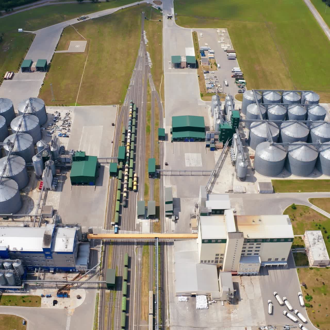 Modern plant with grain elevators on field. Granary for keeping agricultural products. Silver bins for storing crop. Aerial view