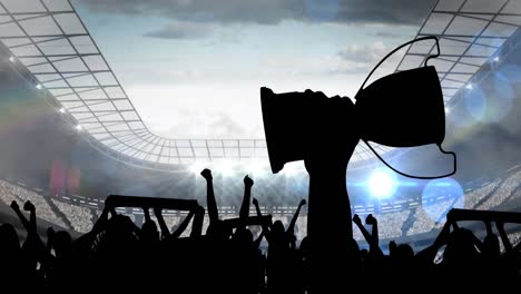 Animation-of-silhouettes-of-sports-fans-cheering-holding-cup-over-sports-stadium