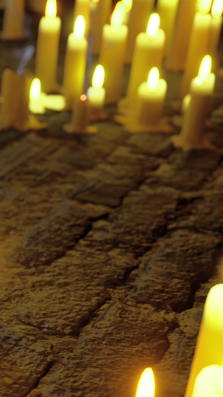 Candele accese su un selciato durante un raduno serale.