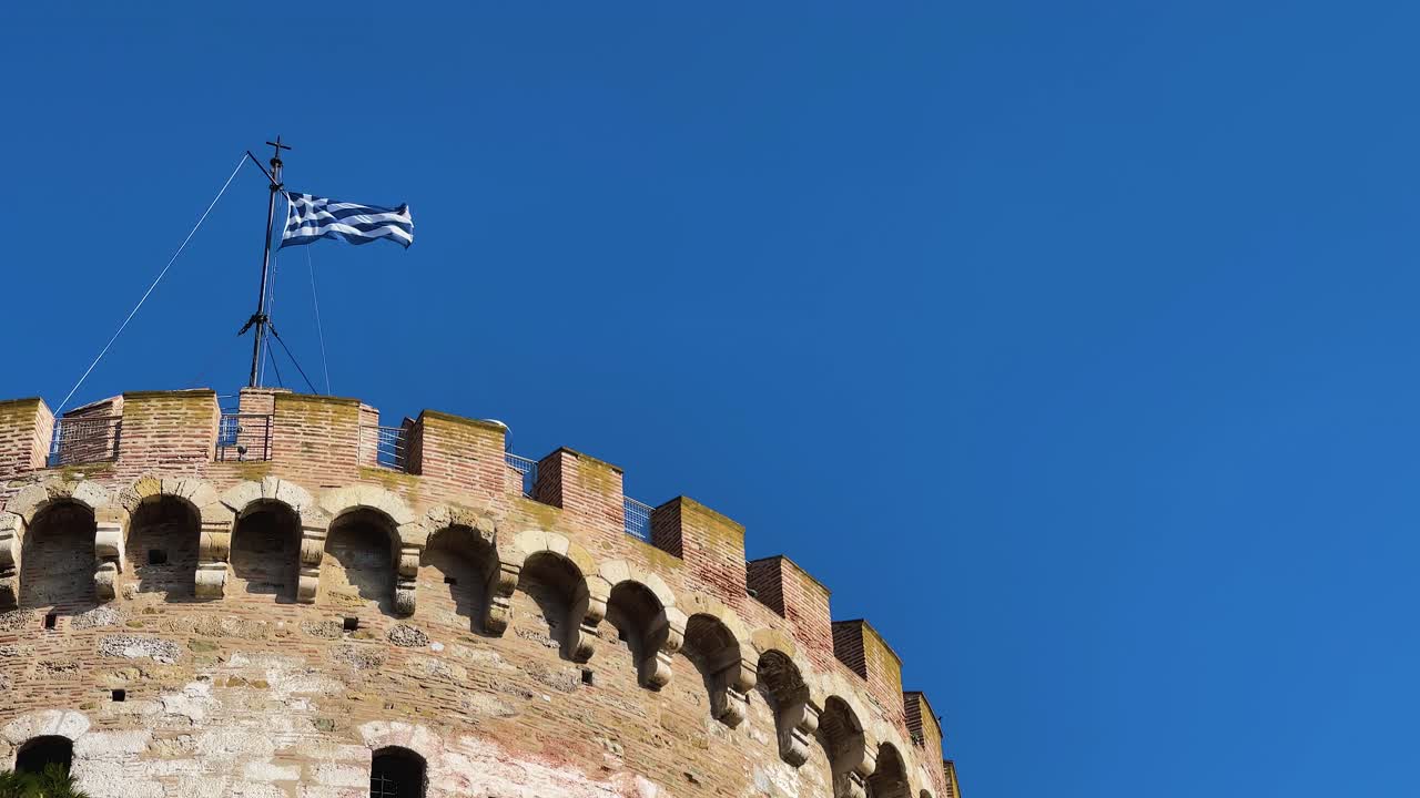 bandera griega en salónica, grecia, en lo alto de la torre blanca.