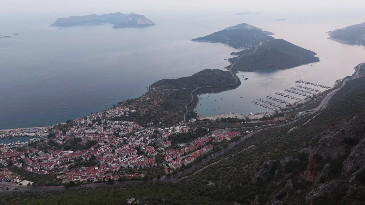 vista panorámica de la bandera turca ondeando en la cima de una colina en kas, antalya, con la costa en el fondo, dolly de establecimiento aéreo