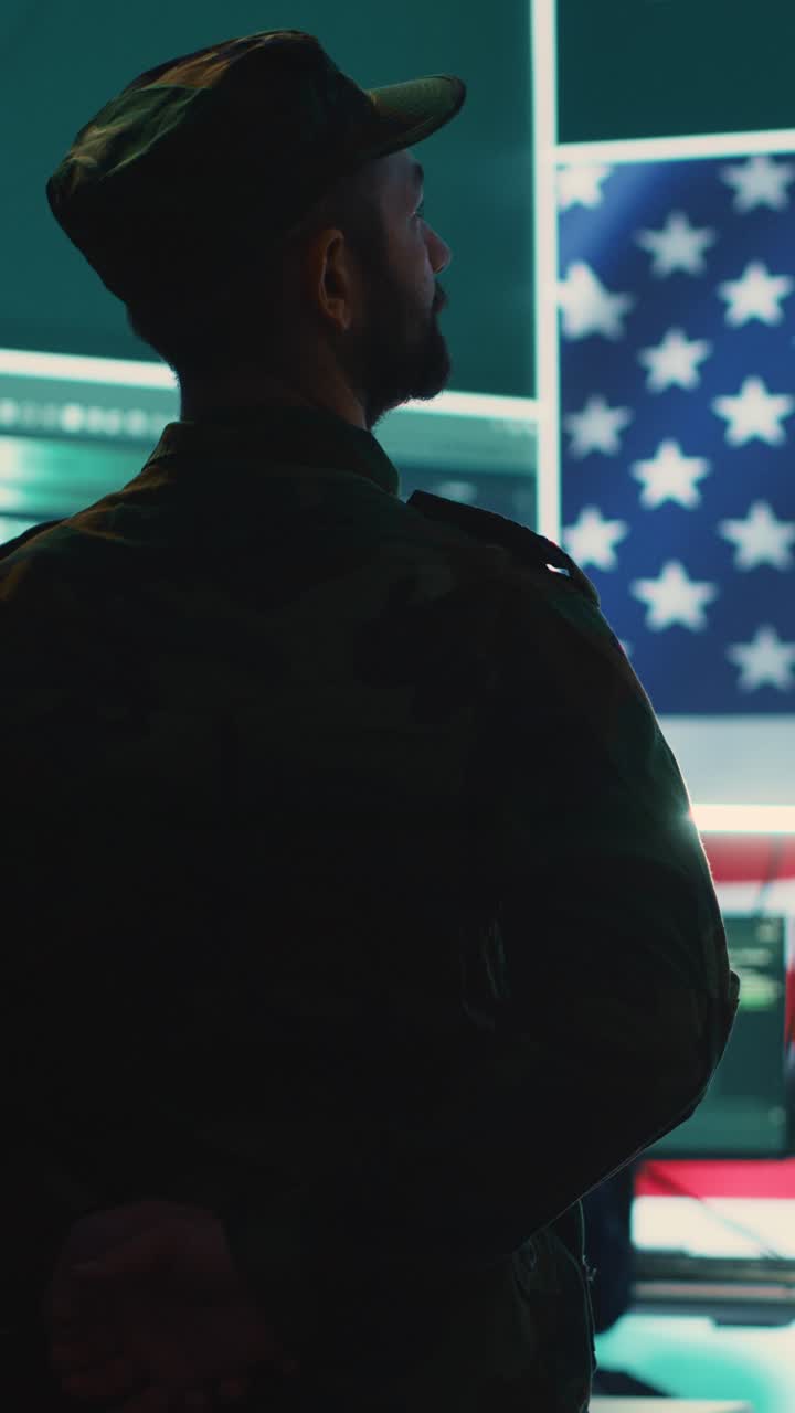 Soldier in Military Uniform Standing in Control Room with American Flag