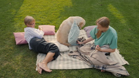 grandmother and granddaughter enjoying a picnic with their dog