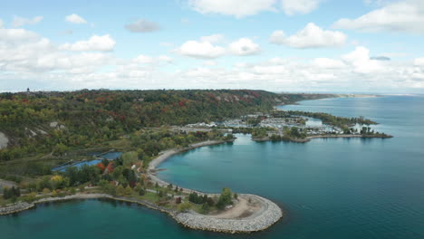 drone shot flying over water towards land, bluffs, peninsula with green trees