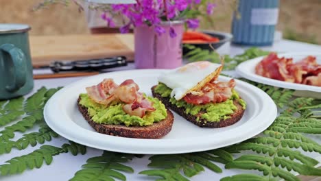golden fried egg placed in slow motion on crunchy toast with guacamole and bacon