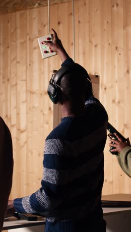 vertical video friends in firing range doing shooting, pressing mechanism to recall targets
