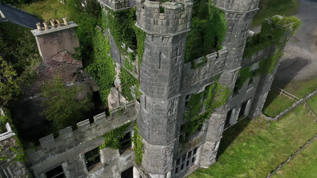 Castle Saunderson, County Cavan, Ireland, September 2022. Drone pulls back and orbits clockwise, from close view to wide of the Ruined Castle with lawns in front with green grass and cloudy sky.