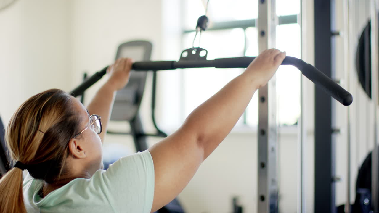 Using lat pulldown machine, woman with disability exercising in gym for rehab