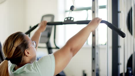 using lat pulldown machine, woman with disability exercising in gym for rehab