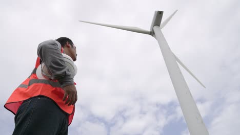 progressive engineer working with the wind turbine, with the sky as background.