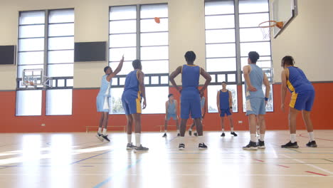 playing basketball, students in gymnasium watching ball near hoop during game