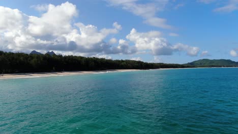 drone-pan-across-tropical-hawaiian-beach-surrounded-by-forest-trees-on-oahu