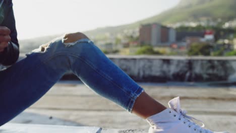 Fashionable-young-woman-on-urban-rooftop-using-smartphone