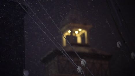 Focus-pull-in-slow-motion-of-snow-falling-in-front-of-a-Japanese-church-at-night