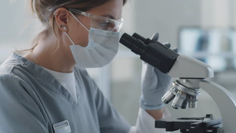 Female-Scientist-in-Medical-Uniform-Using-Microscope