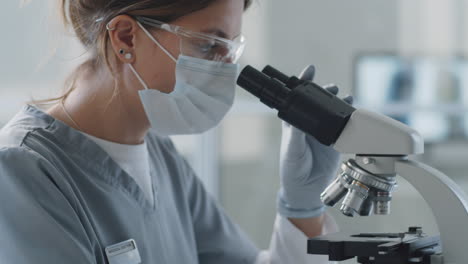 female scientist in medical uniform using microscope