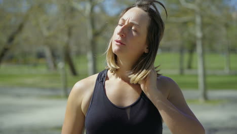 tired young woman drinking water after training in park