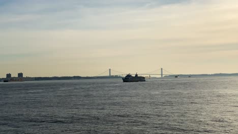 a ferry with tourists in the upper new york bay, verrazzano-narrows bridge in the background