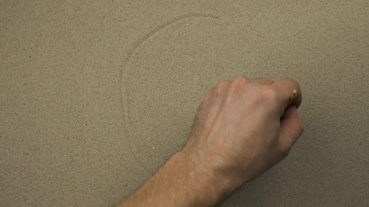 남자 손은 모래에 사람의 중립적인 상징적인 얼굴을 그린다.