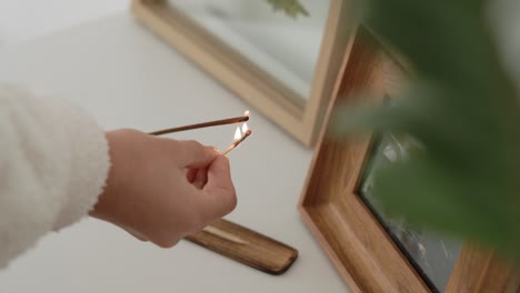female hand lighting up incense on wooden plate with match, frame photograph background