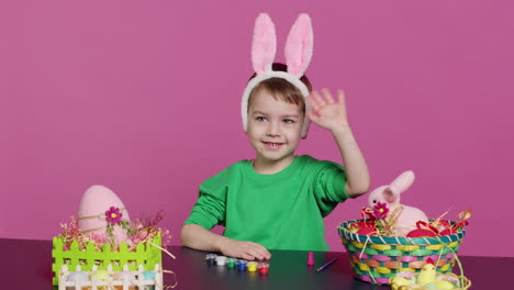 young small kid placing bunny ears on his head in studio