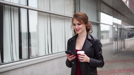 woman walking in city, texting and drinking coffee