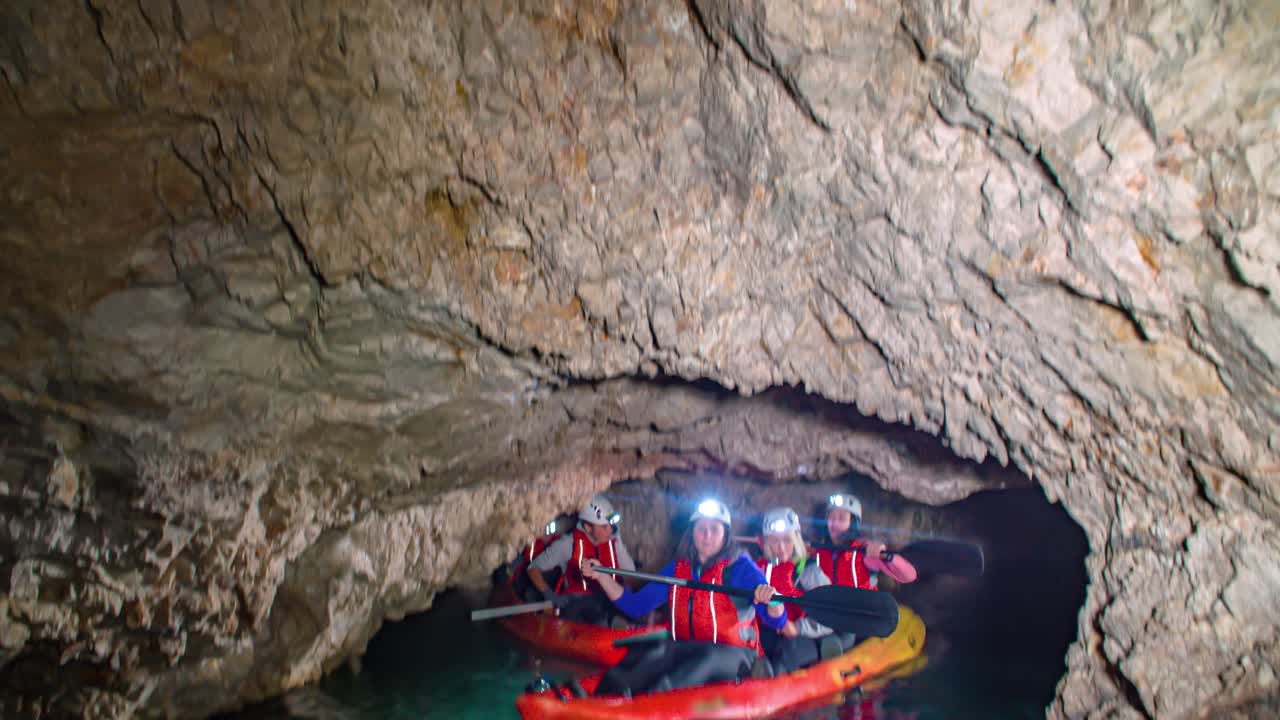 A group of tourists having fun rowling boat in a dark cave