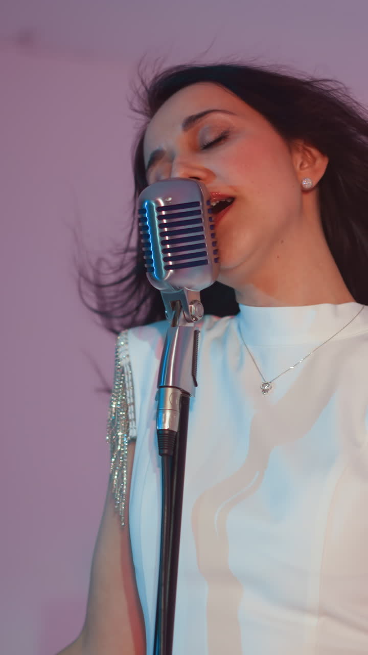 색 드레스를 입은 가수가 빈티지 마이크에 열정적으로 연주하고, 표현적인 손 움직임과 머리카락을 흔들며, 부드러운 색과 분홍색 배경을 배경으로합니다.