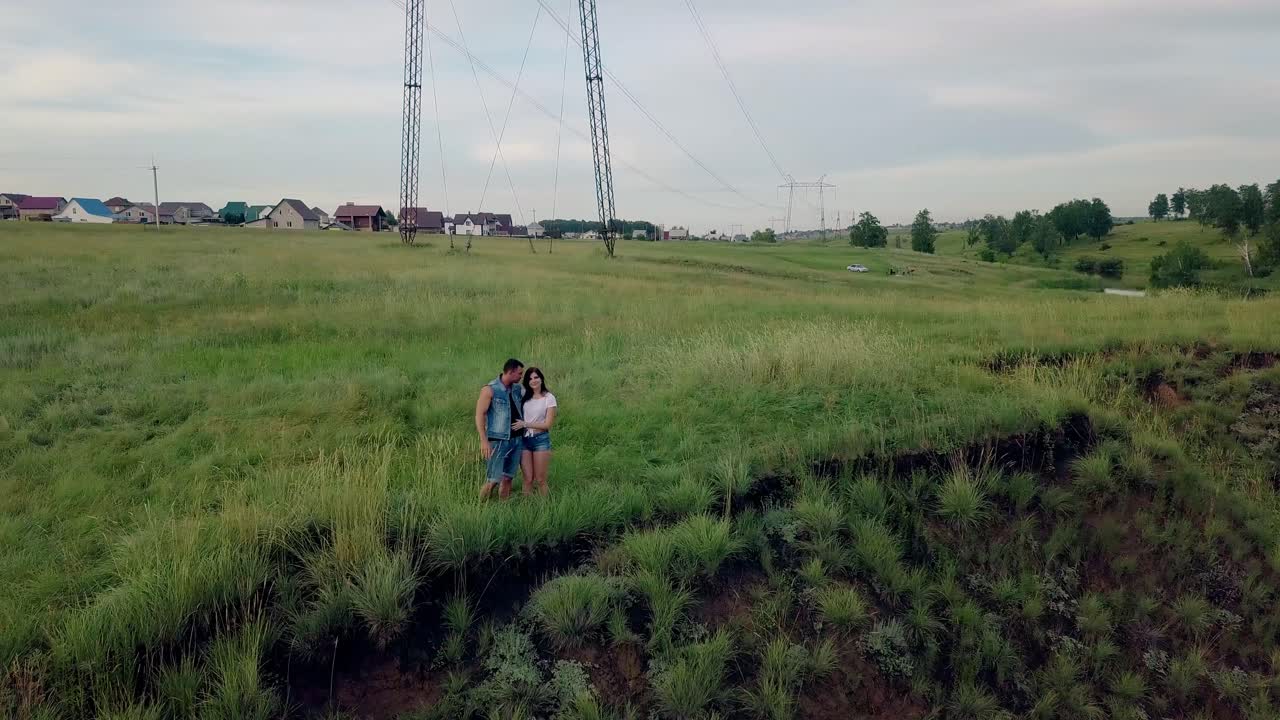 공중 전망 여름 드레싱 젊은 커플이 초원에서 서 있습니다