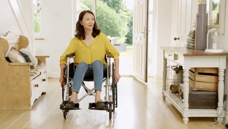 mature asian woman in wheelchair pushing himself in hallway at home towards camera- shot in slow motion