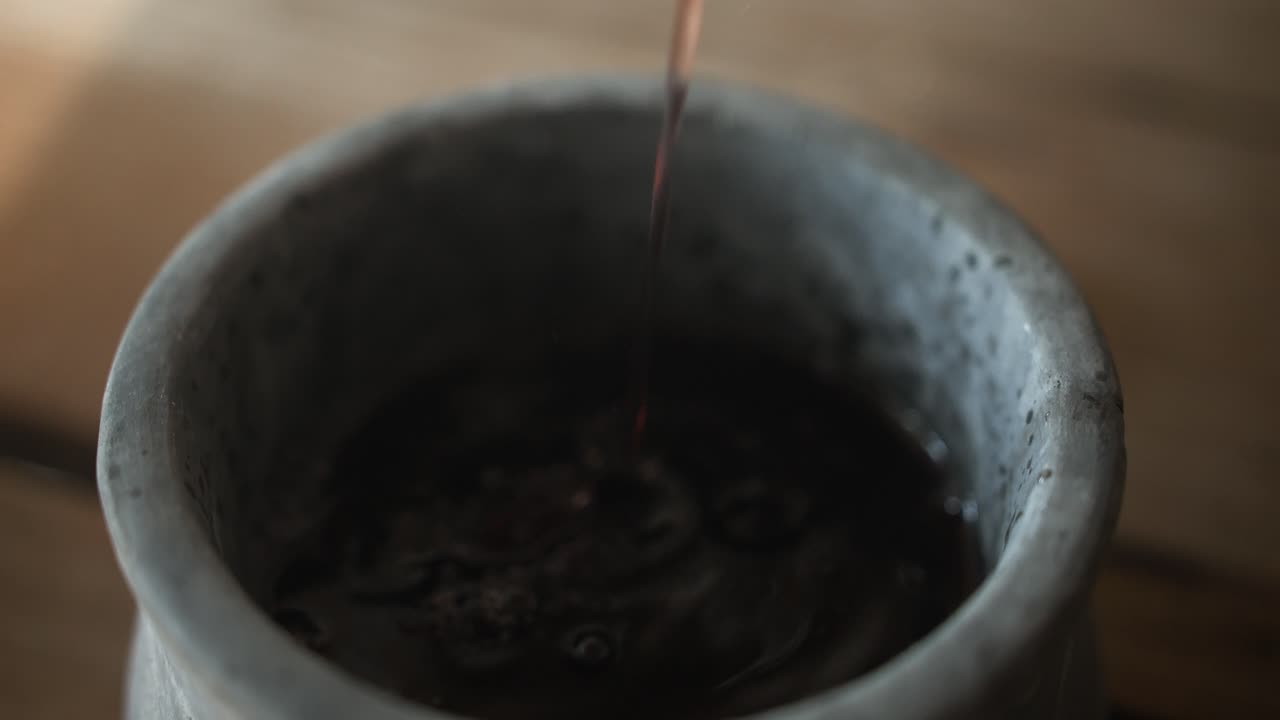 Dark liquid being poured into a bowl