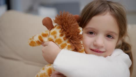 A-little-girl-hugs-her-favorite-toy,-soft-giraffe