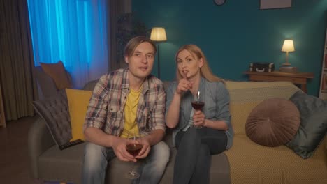 couple relaxing at home watching tv and drinking wine