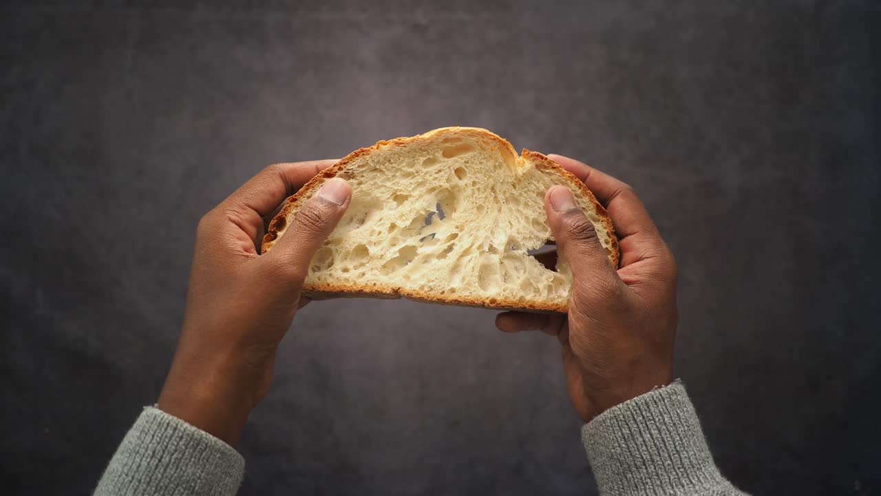 Hands tearing a fresh piece of rustic bread