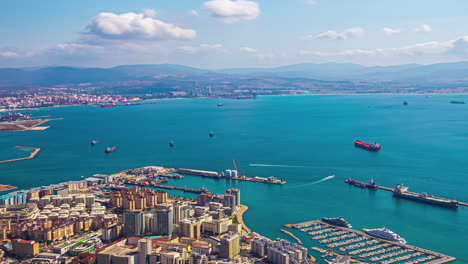 aerial view of coastal cityscape with busy port and moored boats, bright day