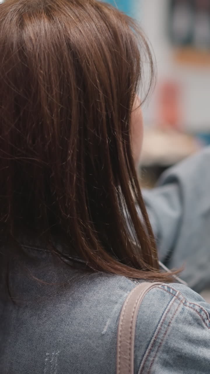 여성은 상점에 전시 된 학교 가방을 가져갑니다. 은 머리 여성은 어린이 가게에서 어린이를위한 학교 용품을 찾습니다. 어머니는 쇼핑몰에서 상품을 선택합니다.