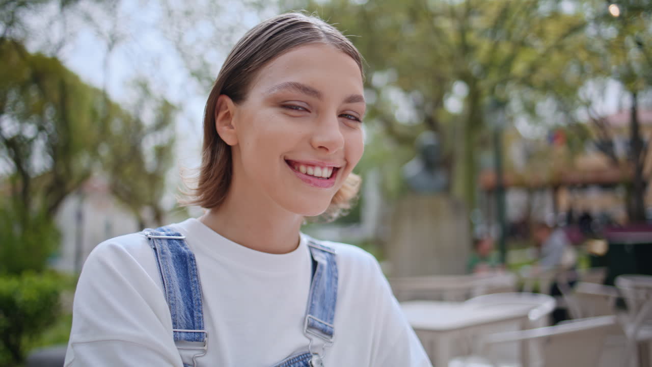 Smiling woman looking camera enjoying outdoors cafe closeup. Portrait happy girl