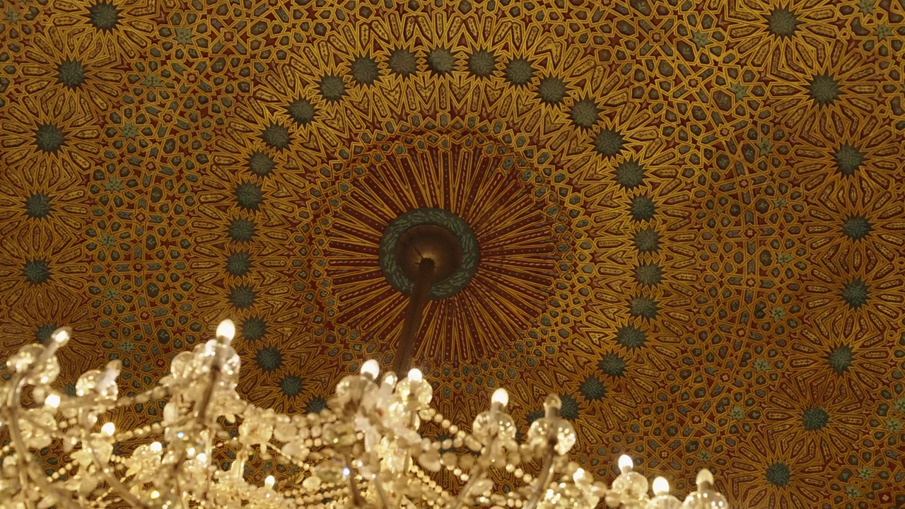 Decorated Moroccan dome ceiling with golden arabesque pattern and crystal chandelier